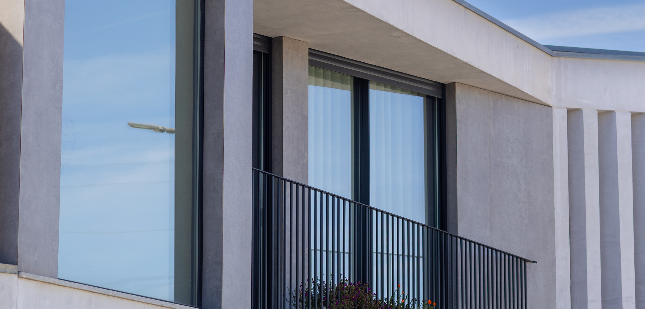 Detalhe construtivo de moradia nas Casas do Alto com pilares em betão aparente e varanda metálica — Contracta Engenharia