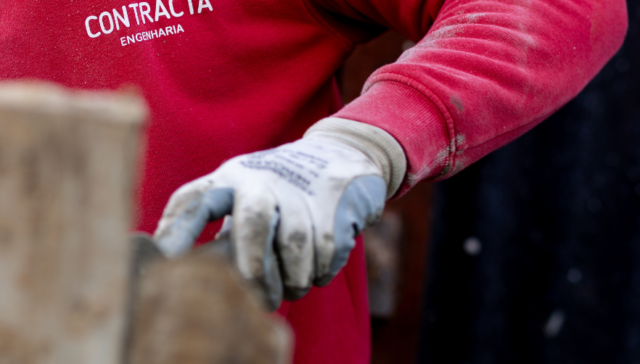 Trabalhador Contracta com luvas de proteção em trabalhos de alvenaria em estaleiro de obra - Contracta