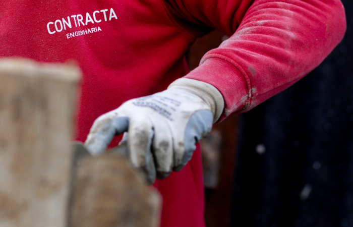 Trabalhador Contracta com luvas de proteção em trabalhos de alvenaria em estaleiro de obra - Contracta