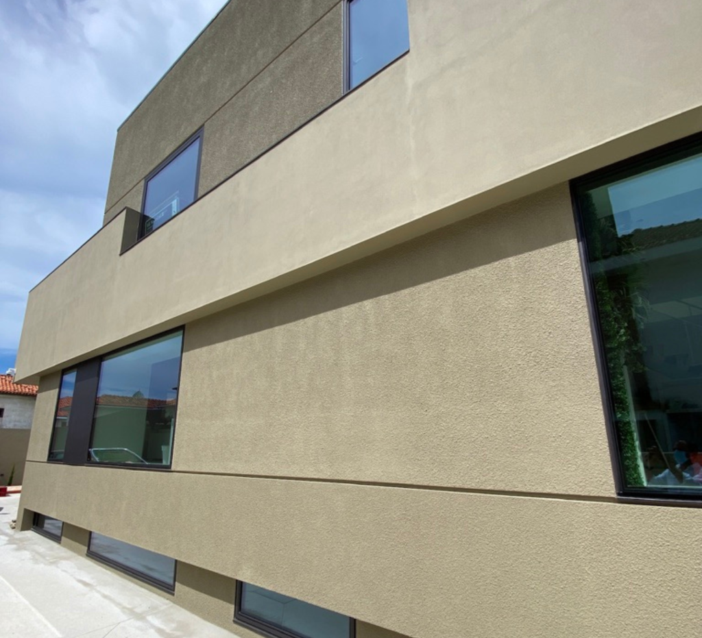 Fachada exterior com revestimento texturado e caixilharia em alumínio - edifício Lacticoop, Aveiro