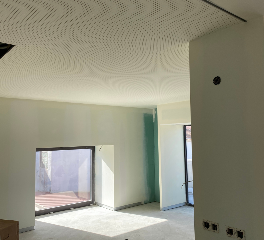 Interior em fase de acabamentos com teto acústico perfurado e grandes vãos envidraçados - sede Lacticoop, construção Contracta
